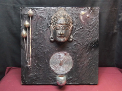 A Buddha Mask on Framed Black Backgrund with Candle Holders.
Size 50x50 Cm.