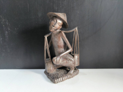 A hard wood carved sculpture , man carrying item on a yoke